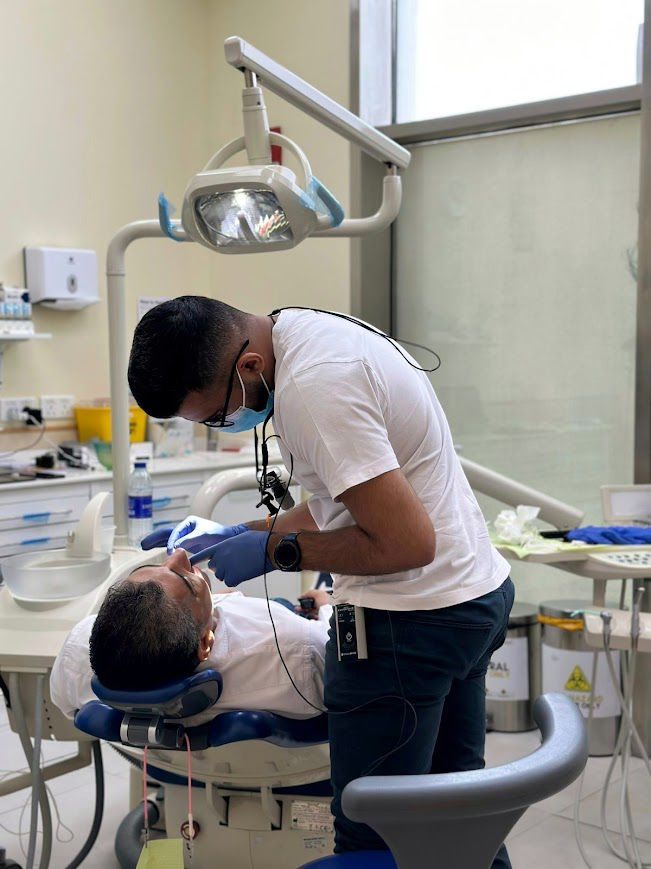 Dr. Maroof Beg working chairside on a patient, wearing loupes while carefully shaping a smile