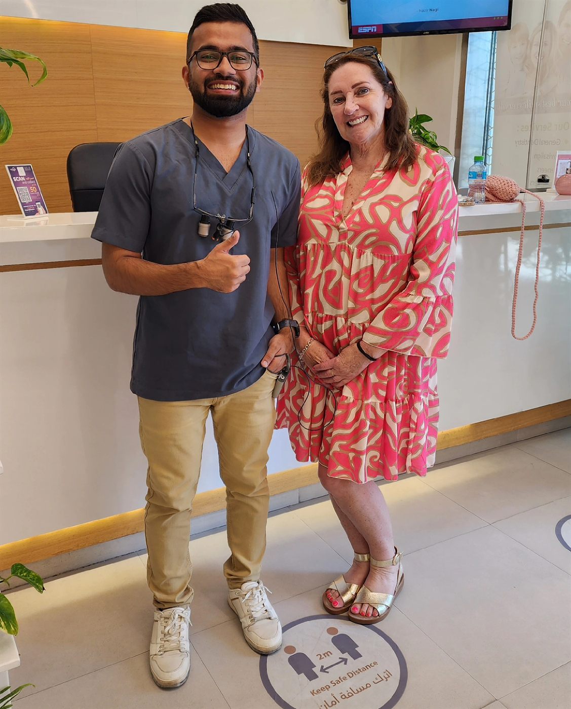 Dr. Maroof Beg with a smiling, happy patient at the clinic front desk